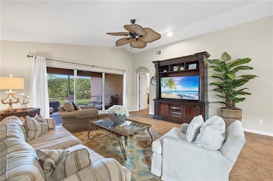 Living room featuring ceiling fan, lofted ceiling, and light tile patterned flooring