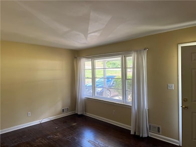 Spare room with dark wood-style floors and baseboards