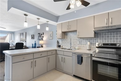 Kitchen with stainless steel appliances, a peninsula, gray cabinets, under cabinet range hood, and ceiling fan