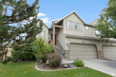 Traditional home with stucco siding, an attached garage, driveway, stone siding, and a front yard