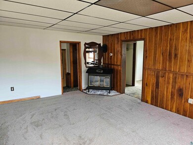 Unfurnished living room with a drop ceiling, a woo