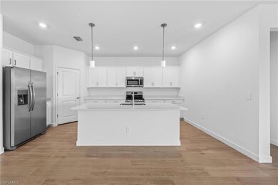 Kitchen with appliances with stainless steel finishes, light countertops, white cabinetry, recessed lighting, and a sink