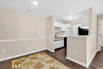 Kitchen with refrigerator, white cabinetry, light countertops, and dark wood-style floors