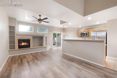 Living room featuring ceiling fan, light wood-style flooring, recessed lighting, and a tile fireplace