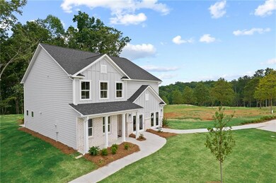 View of front of home with board and batten siding, roof with shingles, a front yard, and covered porch