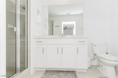 Bathroom featuring light tile patterned floors, a shower stall, and vanity