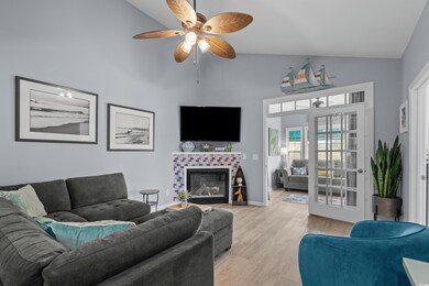Living room featuring lofted ceiling, tiled fireplace, ceiling fan.