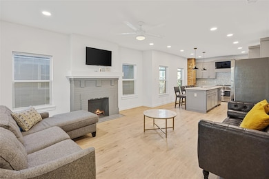 Living area featuring recessed lighting, a brick fireplace, light wood-style flooring, and a ceiling fan