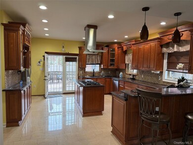 Kitchen featuring backsplash, island exhaust hood, dark stone counters, a peninsula, and recessed lighting