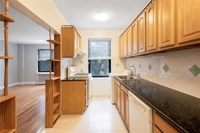 Kitchen featuring open shelves, white appliances, under cabinet range hood, decorative backsplash, and dark stone countertops