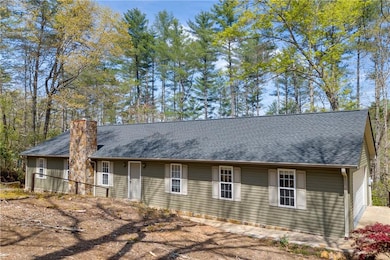Back of house with a chimney and roof with shingles