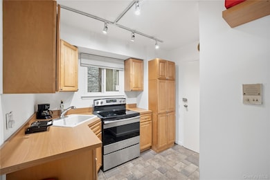 Kitchen with stainless steel range with electric cooktop, stone finish flooring, light countertops, and rail lighting