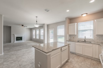 Kitchen featuring a center island, light stone countertops, ceiling fan, decorative backsplash, and recessed lighting
