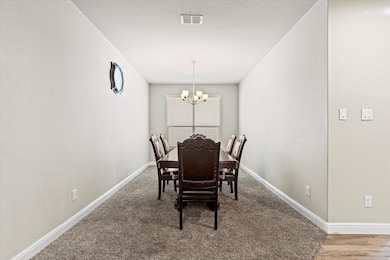Dining area with a textured wall, a chandelier, and carpet floors