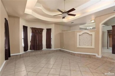 Spare room with arched walkways, ceiling fan, light tile patterned floors, and a raised ceiling