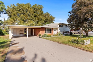 Split level home with a front yard, a carport, driveway, and brick siding