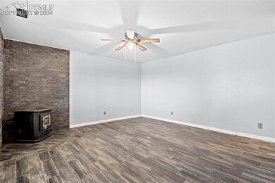 Unfurnished living room featuring ceiling fan, a w