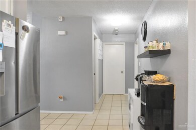 Kitchen with stainless steel refrigerator with ice dispenser, light tile patterned flooring, a textured ceiling, and open shelves
