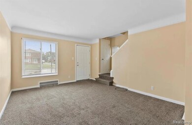 Unfurnished living room with carpet, stairs, and crown molding
