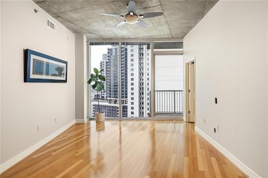 Spare room featuring hardwood / wood-style floors, floor to ceiling windows, a ceiling fan, and baseboards