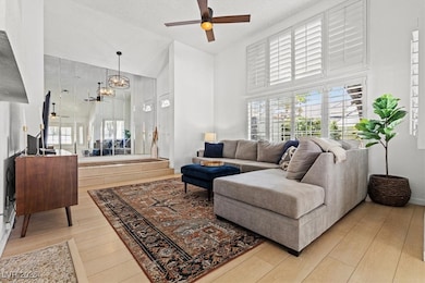 Living area featuring ceiling fan, high vaulted ce