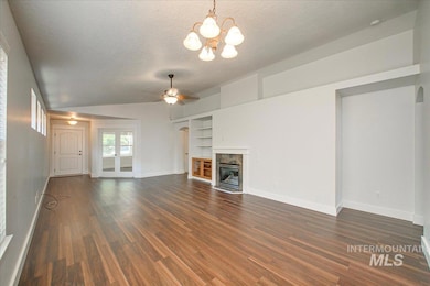 Unfurnished living room featuring a textured ceiling, built in shelves, dark wood-style floors, a high end fireplace, and a ceiling fan