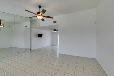 Empty room with a ceiling fan, vaulted ceiling, an