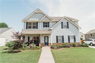 View of front of property with covered porch, a front lawn, stone siding, and a shingled roof
