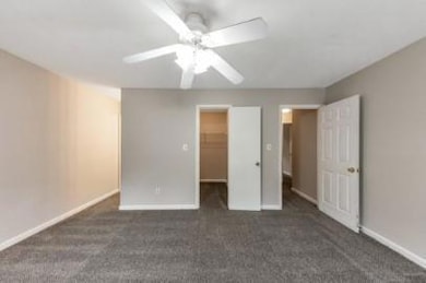 Unfurnished bedroom with a spacious closet, carpet, a closet, and a ceiling fan