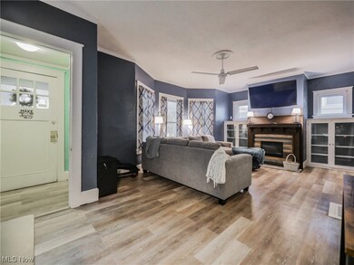 Living room with light hardwood flooring, a fireplace, and ceiling fan