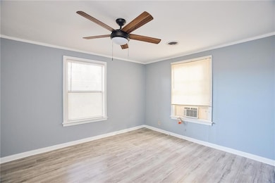 Empty room with a ceiling fan, crown molding, wood finished floors, and cooling unit