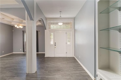 Entrance foyer with arched walkways, wood finished floors, ceiling fan, and baseboards