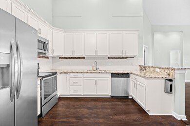Kitchen featuring stainless steel appliances, white cabinetry, and dark wood finished floors