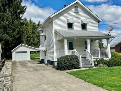 View of front of property featuring a front lawn, a porch, an outdoor structure, and a garage