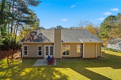 Back of property featuring a lawn, a patio area, a chimney, and roof with shingles