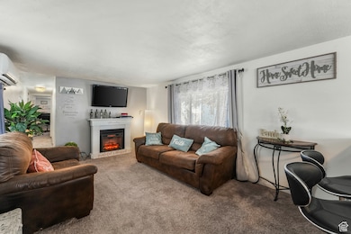 Living room with a glass covered fireplace, carpet, and a wall unit AC