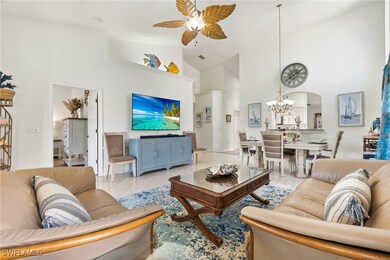 Living area featuring high vaulted ceiling, a ceiling fan, arched walkways, tile patterned flooring, and a chandelier
