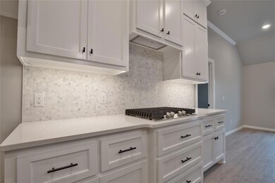 Kitchen featuring light stone counters, tasteful backsplash, light wood-type flooring, white cabinetry, and stainless steel gas cooktop