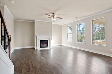 Unfurnished living room featuring ornamental molding, dark wood-type flooring, ceiling fan, stairs, and a glass covered fireplace