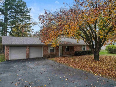 Single story home with a garage, driveway, brick s