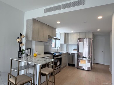 Kitchen featuring stainless steel appliances, a peninsula, light wood-type flooring, modern cabinets, and light stone countertops