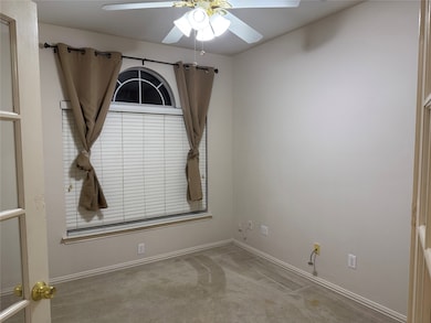 Carpeted spare room with a ceiling fan and baseboards