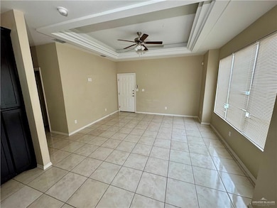 Unfurnished room with baseboards, a raised ceiling, and light tile patterned flooring
