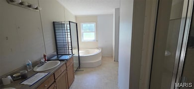 Bathroom featuring vanity, a textured ceiling, a garden tub, and tile patterned flooring