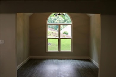Empty room featuring healthy amount of natural light, baseboards, dark wood-type flooring, and a chandelier