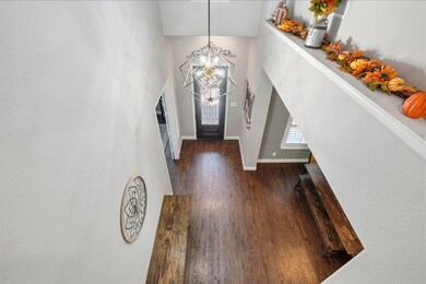 Foyer featuring dark wood-type flooring, a chandelier, and a towering ceiling