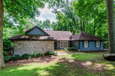 View of front of home featuring stone siding, roof with shingles, and a front yard