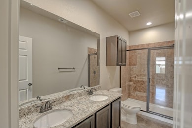 Bathroom featuring double vanity, a stall shower, and recessed lighting