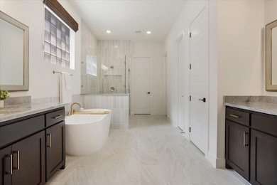 Primary Bathroom featuring a freestanding tub, a large shower, two vanities, and his and hers closets