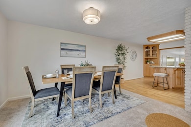 Dining area featuring a textured ceiling, light colored carpet, and light wood-style flooring